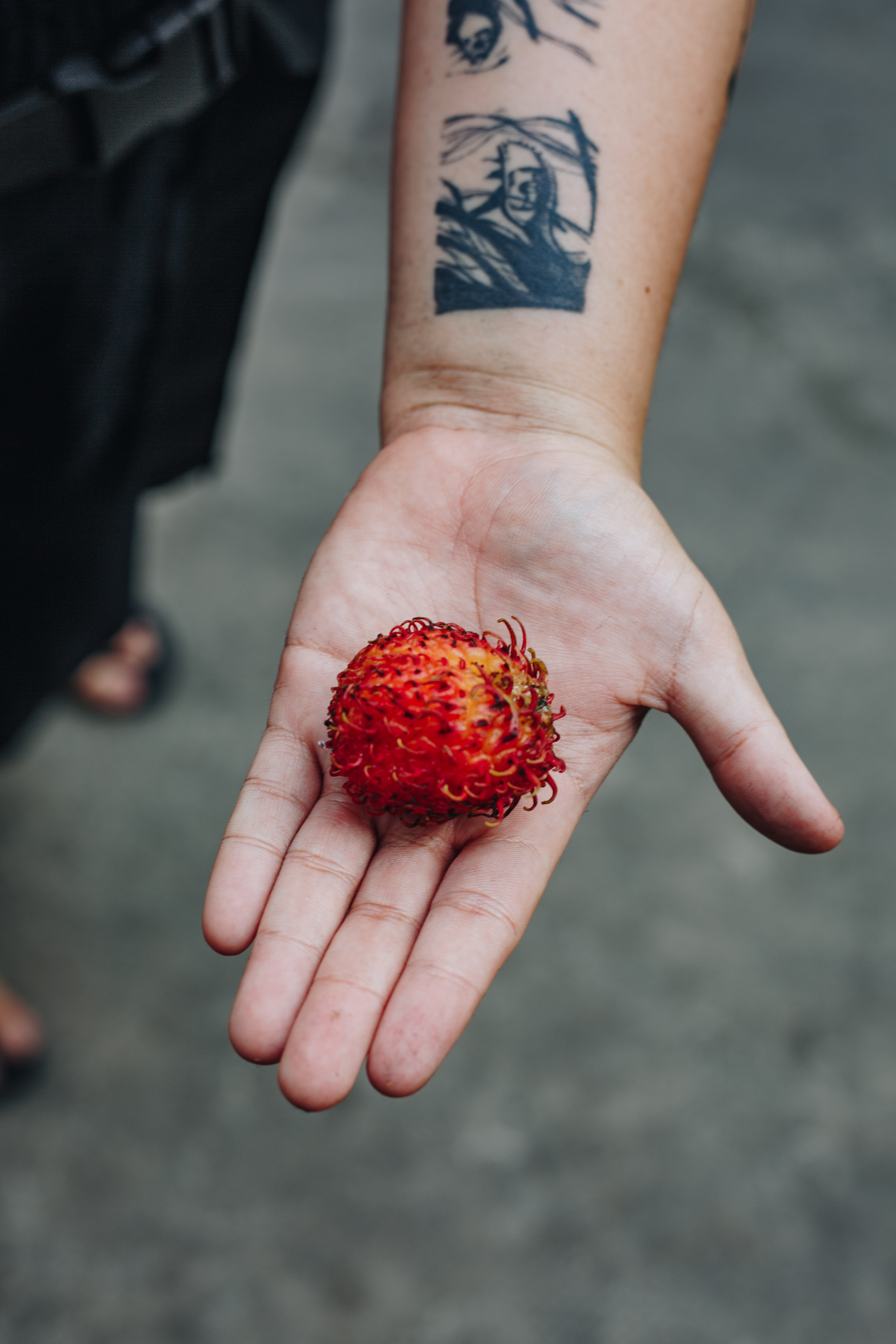A rambutan held in an open palm at a Saigon street market