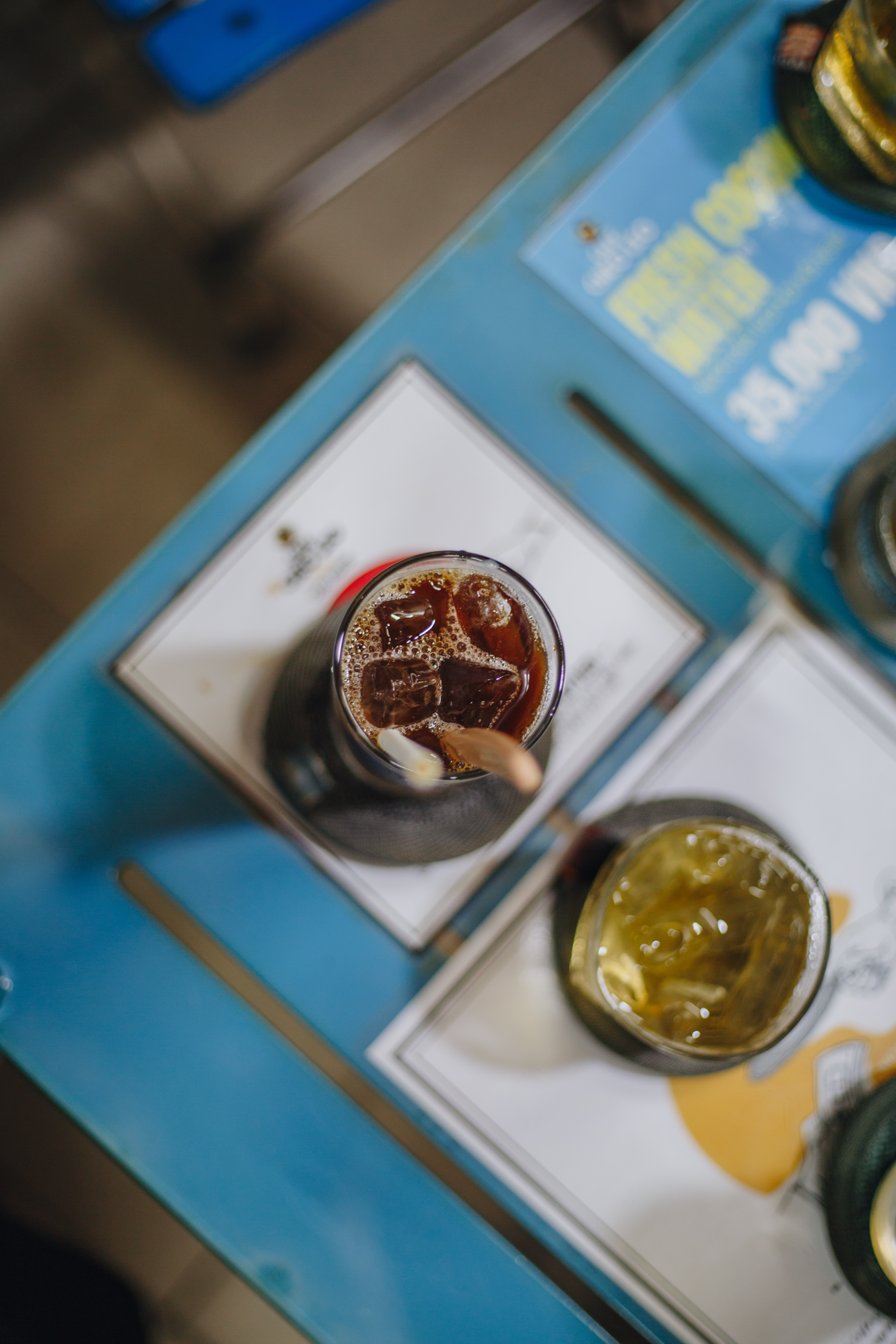 Iced Vietnamese coffee and green tea on a blue cafe table