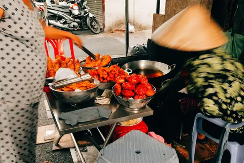 Fried chicken displayed in bowls at a street food stall