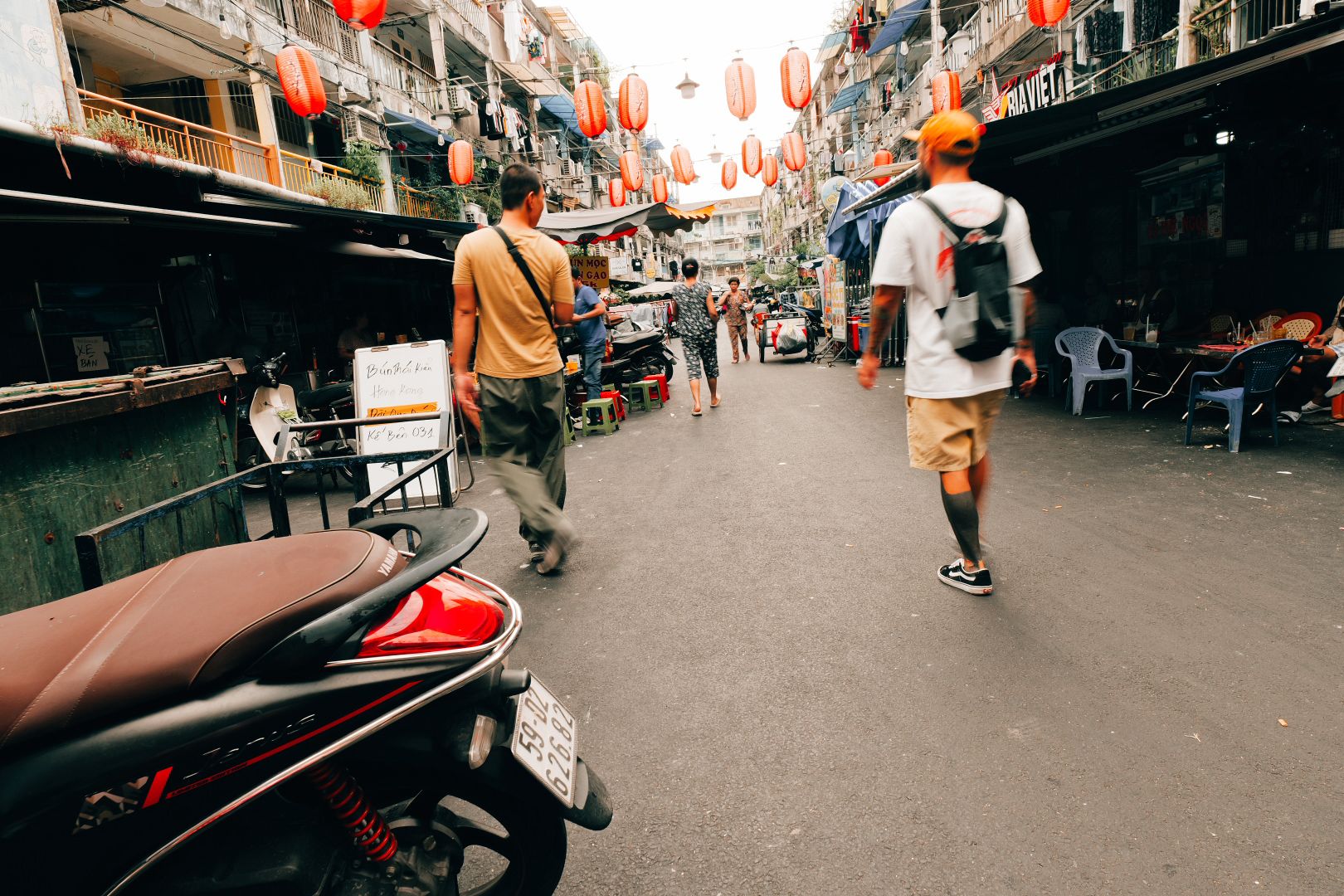 Guests walking through a lantern-lit street food alley in Saigon