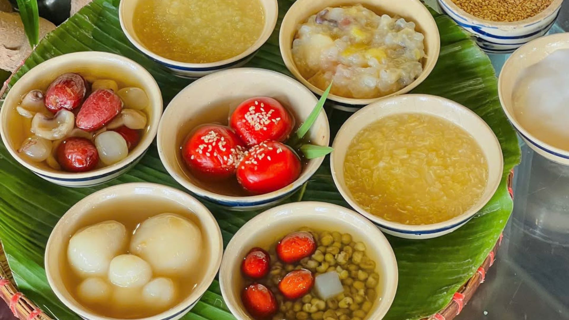 Multiple bowls of Vietnamese che sweet soup on a banana leaf